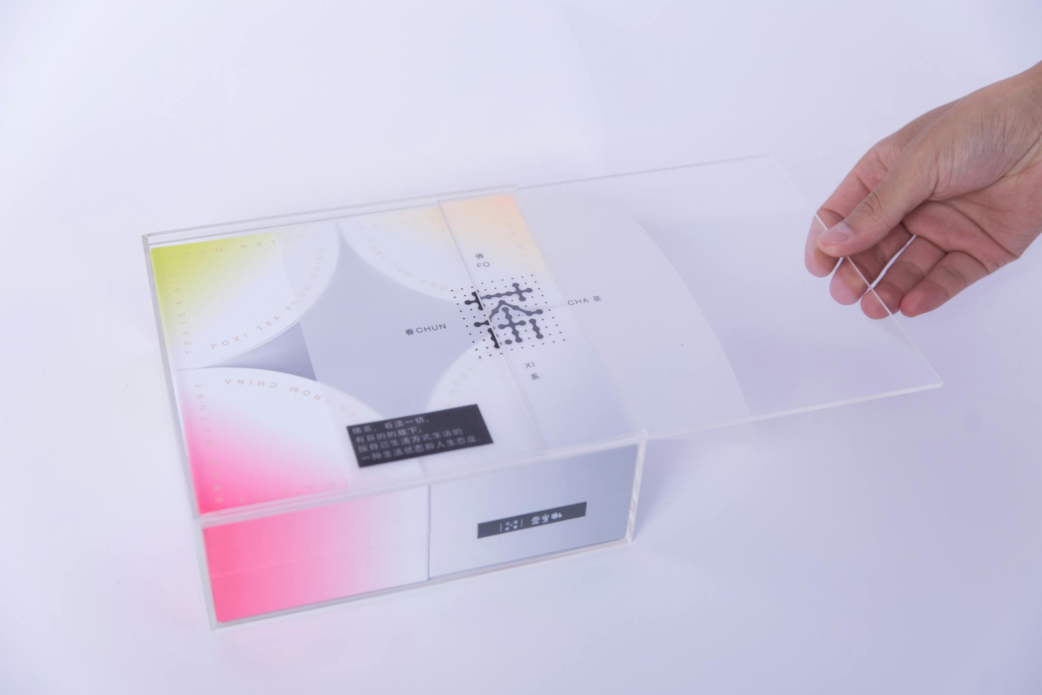 Sleek packaging design with a hand opening a transparent lid, showcasing elegant typography.